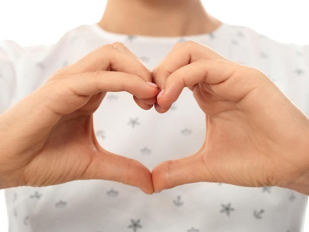 Vista ingrandita delle mani femminili che fanno un gesto a forma di cuore sul petto espressione positiva dell'emozione umana amore caring linguaggio del corpo salute carità concetto di donazione