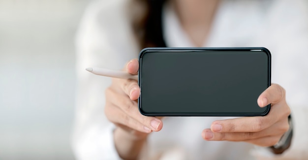 Closeup view of female hands showing blank screen smartphone