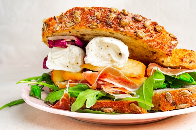 Closeup view of a gourmet Parma ham, mozzarella and peaches sandwich on a plate