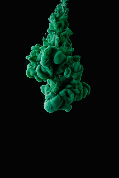 Closeup view of green abstract flowing ink on black background