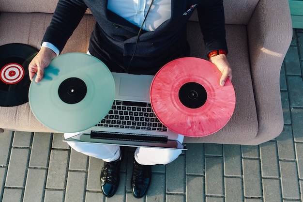 Closeup view. Guy in formal suit, vinyl records and laptop