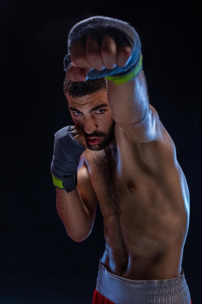 Closeup view on male hands of young athlete in gray bandages black background vertical