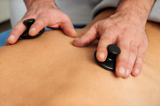 Closeup view of male masseur massaging back and shoulder blades of female lying on massage table at spa salon Beautiful young woman with perfect skin getting relaxing massage