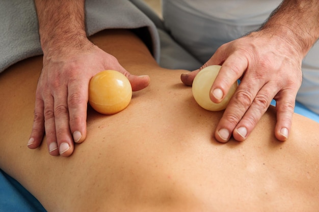 Closeup view of male masseur massaging back and shoulder blades of female lying on massage table at spa salon Beautiful young woman with perfect skin getting relaxing massage