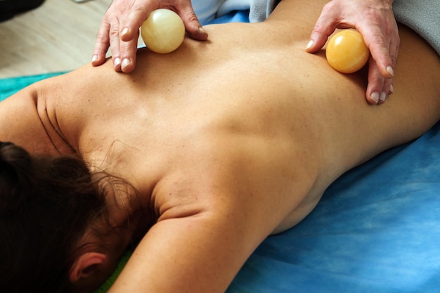 Closeup view of male masseur massaging back and shoulder blades of female lying on massage table at spa salon Beautiful young woman with perfect skin getting relaxing massage