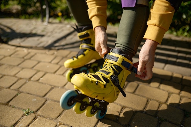 Closeup view of man putting on roller skates while sitting on bench in park