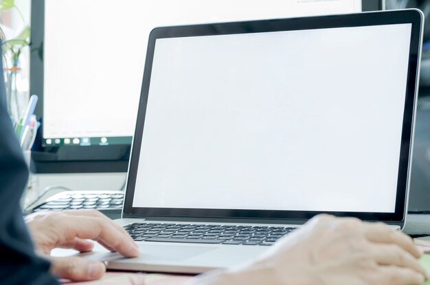 Closeup view man using laptop show blank screen while sitting at office desk.