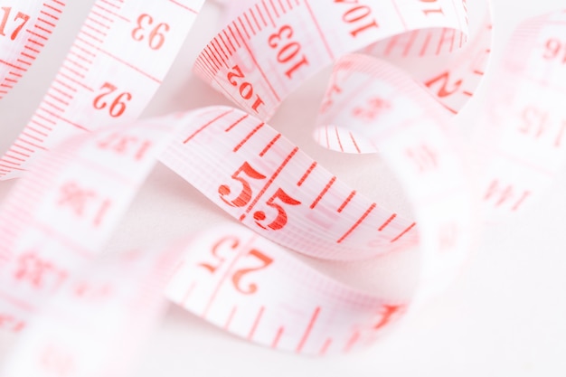 Closeup view of measuring tape on white paper background