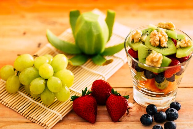 Closeup view of a mixed and fresh colorful fruit salad in a glass cup Fresh fruit on wooden table