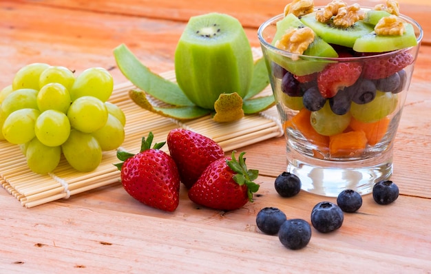 Closeup view of a mixed and fresh colorful fruit salad in a glass cup Fresh fruit on wooden table