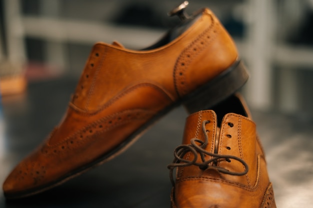 Closeup view of old light brown leather shoes with wooden shoe
pad to be repaired in dark craft shoe...