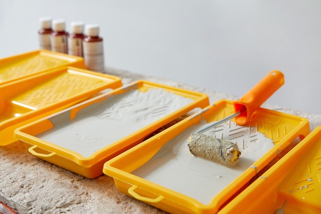 Closeup view of paint tray filled with gray paint tools for the painter and redecoration