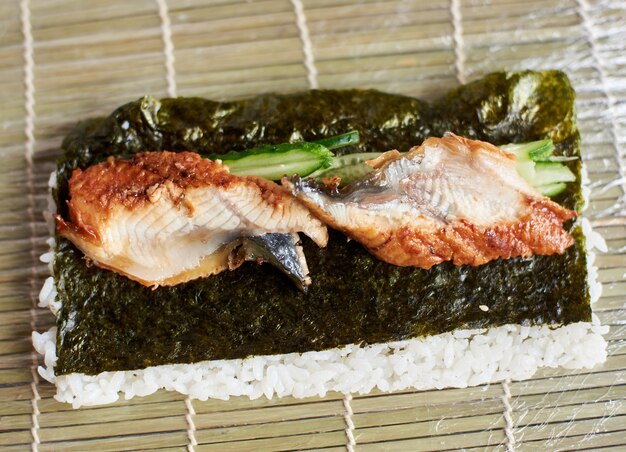 Closeup view of process of preparing rolling sushi