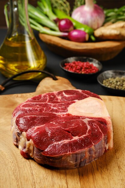 Closeup view of raw beef shank crosscut on chopping board with ingredients for cooking