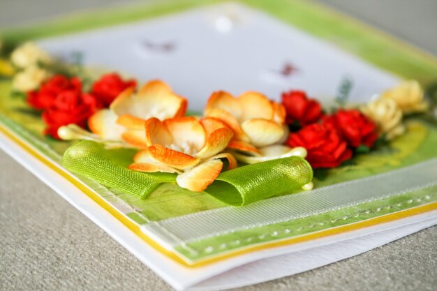 Closeup view of a scrapbooking card with paper flowers, ribbons and hand stitching