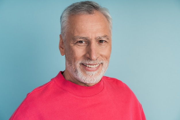 Closeup view, senior man smiling wearing a bright pullover.