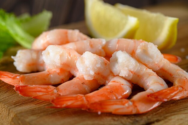 Photo closeup view of shrimps with lemon and green dill on wooden table