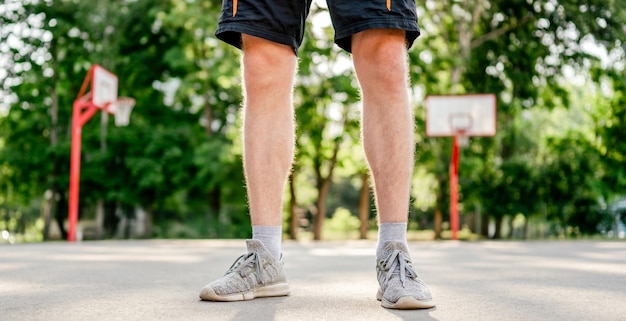 Closeup view of sportive man guy legs during training at the stadium outdoors. Adult male person workouts in summertime. Sportsman exercising outside