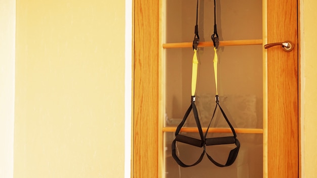 Closeup view of suspension on door on wooden background training at home - Fitness at home