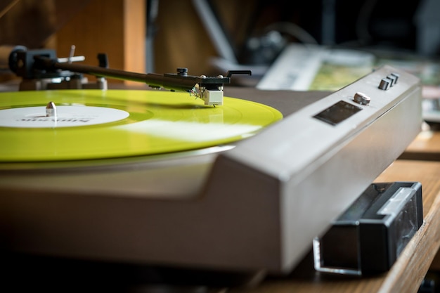 Closeup view of a tonearm and turntable playing color yellow vinyl record Entertainment and music trends