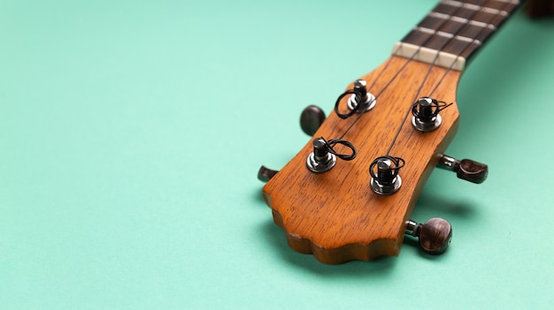 Closeup view of ukulele headstock. Cyan background copy space.