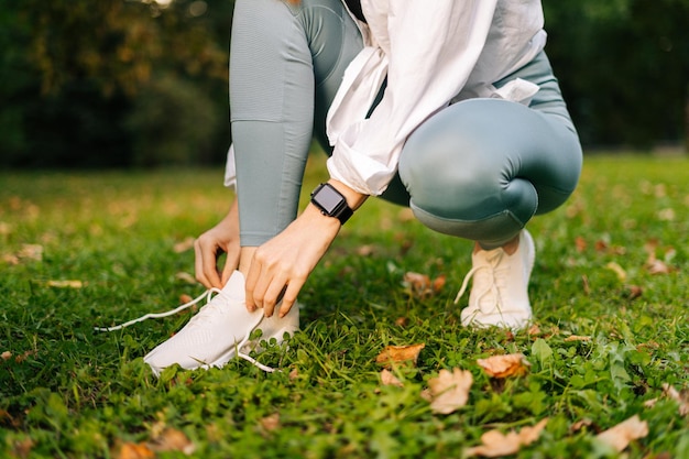 Closeup view of unrecognizable young woman tying shoelaces on sneakers before running Female tying laces on footwear and ready for trainingConcept of healthy lifestyle and sports training alone