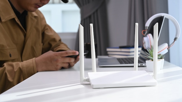 Photo closeup view of a wireless router with businessman using laptop computer and smart phone in home office background .