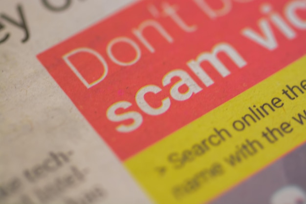 A closeup view of the wording Scam prominently displayed on a newspaper