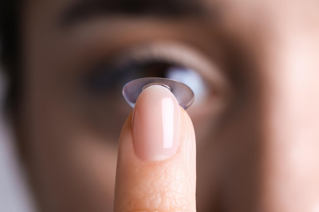 Closeup view of young woman putting contact lens in her eye