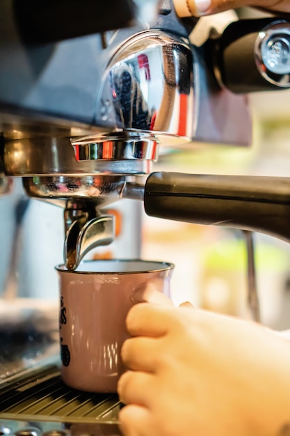 Closeup of a vintage mug in an espresso machine with hot coffee coming out of the spout vertical photo