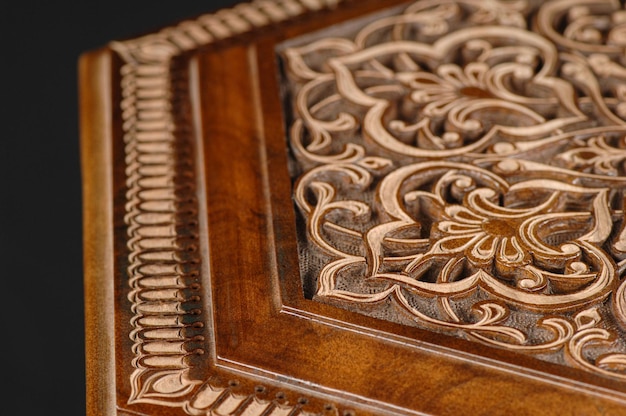 The closeup vintage oriental wooden table with the artistic carving on a black background Uzbekistan