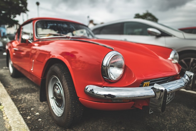 Foto primo piano vintage auto rossa irlanda del nord scena luminosa il veicolo retrò scarlatto sul cielo nuvoloso