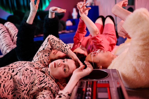 Closeup of vogue dance crew lying on floor in red neon light\
focus on gril with glitter makeup looki