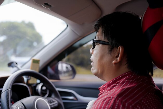 Closeup volwassen Aziatische man met stress of angst of droevige gezichtsuitdrukking tijdens zitten en autorijden in het verkeer. GPS-navigator op mobiele telefoon. verlies krijgen. bril man op slechte reis