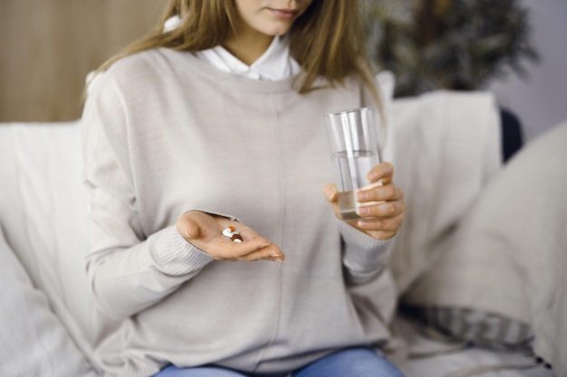 Closeup vrouw met pillen tijd om medicijnen te nemen remedie voor hoofdpijn hoge bloeddruk pijnstillers medicijnen thuis Blijf thuis concept tijdens Coronavirus pandemie