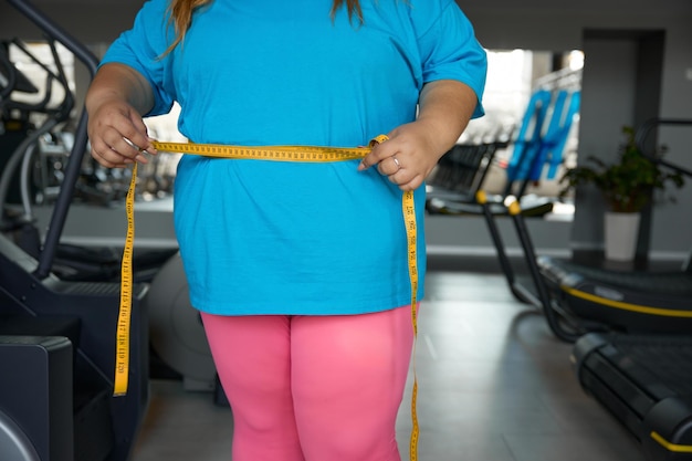 Foto immagine ravvicinata della vita di una donna grassoccia avvolta in nastro misurante sport di allenamento e programma di dimagrimento per le persone con obesità