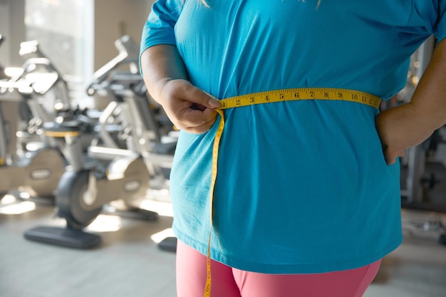 Closeup waistline of overweight woman wrapped in measuring tape