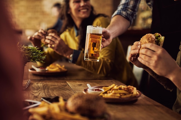 Крупный план официанта, подающего пиво гостям, которые едят в пабе