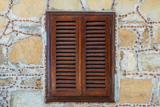 Foto closeup muro di una casa in pietra con finestre e persiane in legno vecchia architettura europea