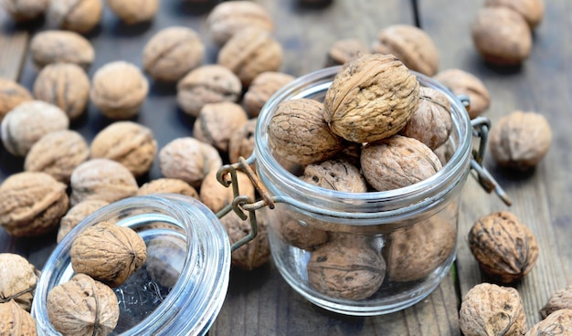 Closeup on walnuts in a glass jar among others on wooden table