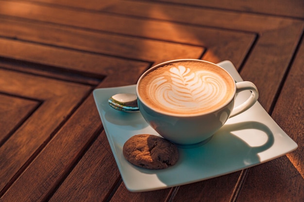 Closeup warme cappuccino witte koffiekopje met hartvorm latte art op donkerbruine oude houten tafel