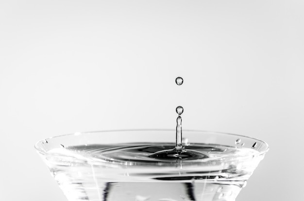 Closeup of water drop falling into a glass on white background