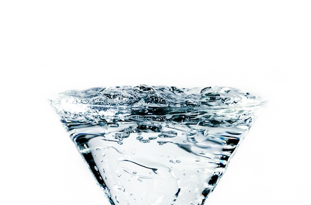 Closeup of water drop falling into a glass on white background