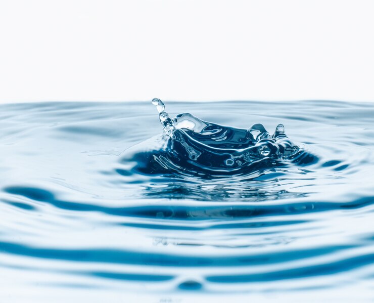 Фотография крупным планом капли воды, падающие в стакан