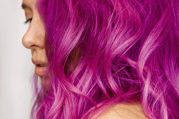 Primo piano dei capelli ondulati viola caldo di una giovane donna risultato della colorazione