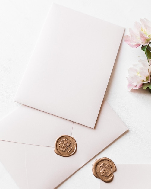 Closeup of wedding envelopes with wax seals and flowers on a white background