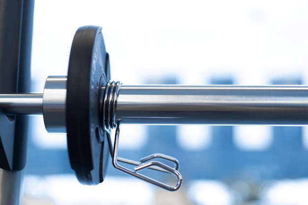 Photo closeup weight plate fixed on barbell in gym