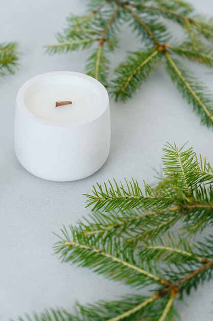 Closeup White Candlestick with Soy Wax on Concrete Background Among Green Christmastree Branches