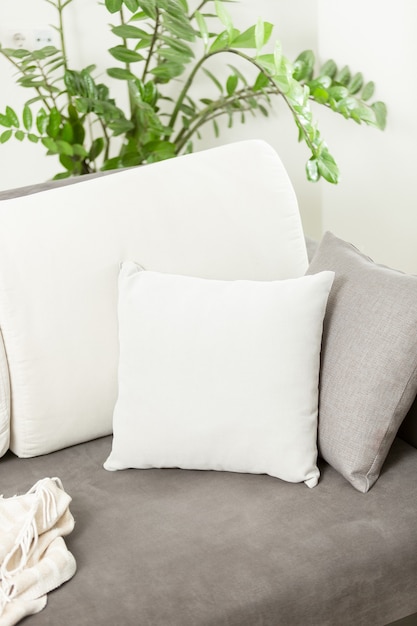 Closeup white decorative cushion lying on gray sofa at living room