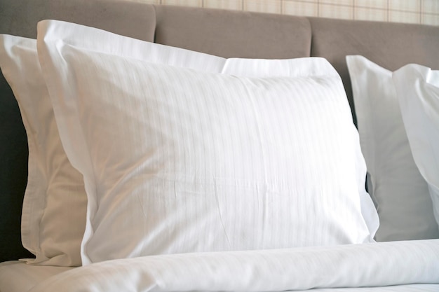 Крупный план белых подушек на кровати в гостинице белая чистая подушка в комфортабельном номере